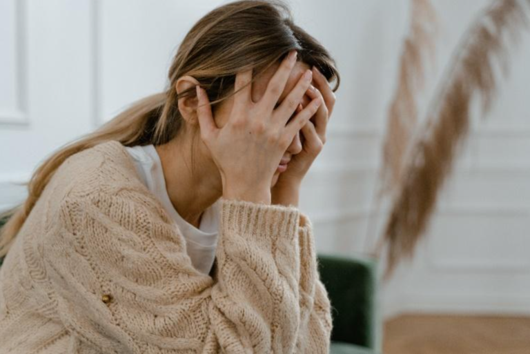 A stressed woman sits with her head in her hands.